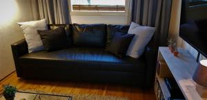 a black leather couch with pillows in a living room at De Vuurplaats in Drachten