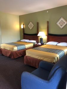 a hotel room with two beds and a chair at Budget Inn Williamsport in Williamsport