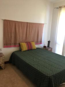 a bedroom with a green bed and a window at Condomínio Reserva Imbassai in Imbassai