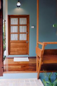 Habitación con puerta de madera y silla de madera. en Paiyannoi Guesthome en Chiang Mai