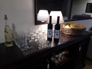 Hostel Franica في Kuršumlija: طاولة مع زجاجات النبيذ والاكواب وسلة من الفواكه