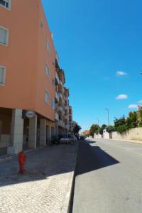 um hidrante vermelho numa rua ao lado de um edifício em Quinta dos Lombos em Carcavelos