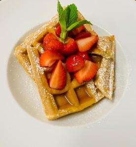 a plate of waffles with strawberries and powdered sugar at Wyndham Garden Ft Lauderdale Airport & Cruise Port in Dania Beach
