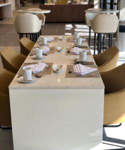 a long table with cups and saucers on it at Wyndham Garden Ft Lauderdale Airport & Cruise Port in Dania Beach