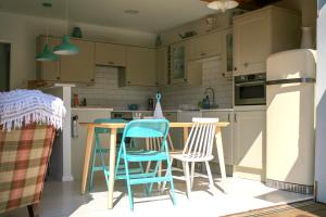 a kitchen with chairs and a table and a refrigerator at Owlers Retreat in Camber