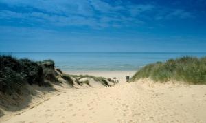 un camino de tierra que conduce a una playa con el océano en Owlers Retreat en Camber
