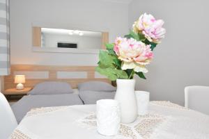 a white vase with pink flowers on a table at Pokoje Gościnne Nowa Grań in Zakopane