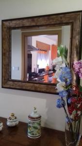 Un espejo en una pared con un jarrón de flores sobre una mesa. en Casa Da Fonte Da Torre, en Peso da Régua