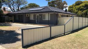 een huis met een wit hek ervoor bij Maddington House Unit C in Perth