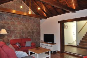 a living room with a red couch and a tv at Casa Guayarmina in Tejeda