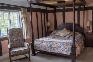 a bedroom with a four poster bed and a chair at St Mary’s Bed & Breakfast in Bury Saint Edmunds