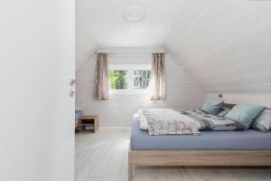 łóżko w białym pokoju z oknem w obiekcie Kotwica-Pobierowo Bukowa 1 w Pobierowie