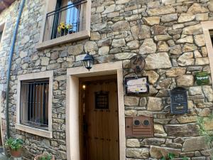 a stone building with a door and a sign on it at El Bulín de Braojos - 3 Casas in Braojos de la Sierra
