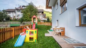 un patio trasero con un parque infantil con un juego de juegos en Apartments Chalet Maria en Badia