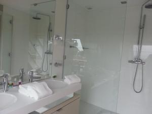 a white bathroom with a shower and a sink at Le Churchill Hôtel & Spa in Carnac
