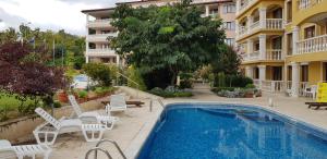a swimming pool with white chairs and a building at Byala Palace Apartments in Byala