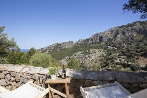 un patio con mesa, sillas y pared de roca en Villa Es Coco, Soller, en Puerto de Sóller