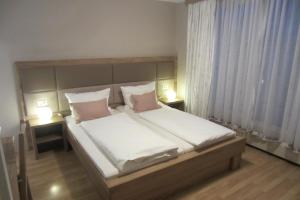 a bedroom with a large white bed with two lamps at Homestay Sreš in Mlaka pri Kranju