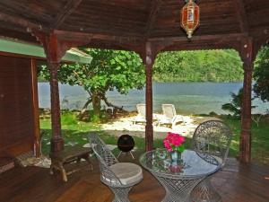 a porch with a table and chairs and a view of the water at Robinson's Cove Villas in Papetoai