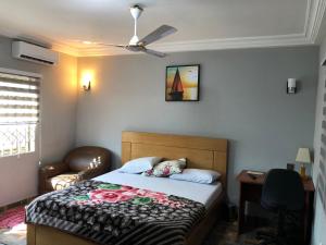 a bedroom with a bed and a ceiling fan at Bonsukoda Lodge in Accra