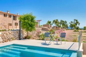 uma piscina com duas cadeiras e uma mesa ao lado de uma casa em Villa Amazing Vilafranca em Vilafranca de Bonany