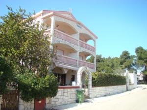 a large house with a balcony on a brick wall at Apartmani Nena in Povljana