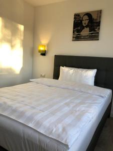 a large white bed in a bedroom with a picture on the wall at Hotel52 Bergheim in Bergheim