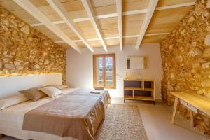 a bedroom with a bed and a stone wall at VILLA ES TRENC - Sa Sinia Vella in Campos