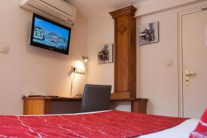 a hotel room with a television and a bed at Hôtel De La Cloche in Obernai