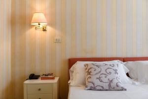 a bed with a pillow and a lamp on a night stand at Hotel Continental in Treviso