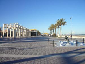 a cobblestone street with palm trees and a beach at Holiday Apartments Malvarrosa Beach in Valencia
