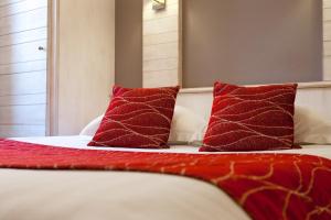 a bed with two red pillows on top of it at Hôtel De La Cloche in Obernai