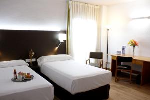 a hotel room with two beds and a desk at Pacoche Murcia in Murcia