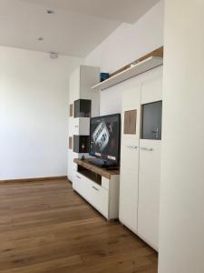 a living room with a tv and white cabinets at Ferienwohnung Kohls in Steinheim