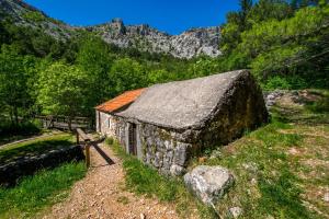 an old stone barn with an orange roof on a mountain at Apartman Amarena in Starigrad-Paklenica