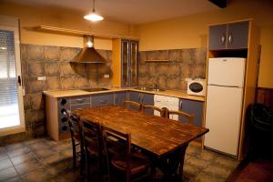kuchnia z drewnianym stołem i lodówką w obiekcie Apartamentos Río Madera w mieście Segura de la Sierra