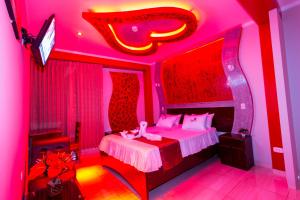 ein rosafarbenes Schlafzimmer mit einem Bett mit rosafarbener Beleuchtung in der Unterkunft Hotel Suite Naylamp Zyon in Jaén