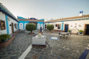 a courtyard with blue and white buildings with tables and chairs at Cortijo los Llanos in Luque