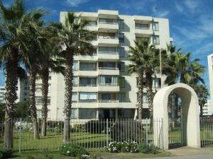 un edificio con palmeras frente a una valla en DEPTO 1RA LINEA FRENTE AL MAR Condominio Palmar 4P, en La Serena