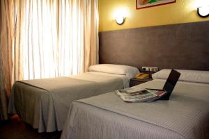 a hotel room with two beds and a chair at Hotel Universal Murcia in Murcia