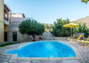- une piscine avec des chaises et un parasol dans l'établissement Villa Dimitris, à Kalamitsi Amygdali