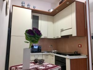 eine Küche mit weißen Schränken und einer Vase lila Blumen in der Unterkunft Casa Gamilia in Neapel