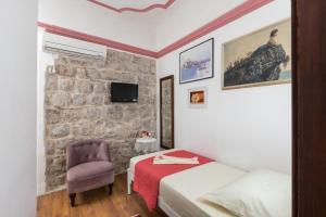 a bedroom with a bed and a chair and a stone wall at guesthouse Vicelic in Dubrovnik
