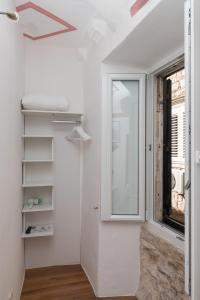 Habitación con ventana, paredes blancas y espejo. en Guesthouse Vicelic, en Dubrovnik