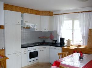 a small kitchen with white cabinets and a table with a table at Haus Klinger in Gaschurn
