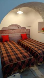 a bedroom with two beds with red pillows at Trulli in Valle D'Itria in Cisternino