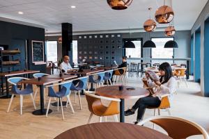 un grupo de personas sentadas en mesas en un restaurante en B&B HOTEL Zürich Airport, en Rümlang