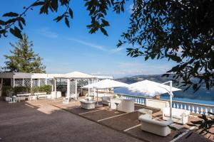 a patio area with a patio table, chairs, and umbrellas at Hotel Castel Vecchio in Castel Gandolfo