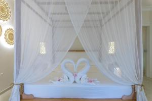 ウジェントにあるIl Lusso Del Silenzioのベッド(カーテン付)に座る白いタオル2枚