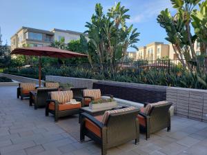 eine Terrasse mit Stühlen, Tischen und einem Sonnenschirm in der Unterkunft Penthouse Dreams in Irvine